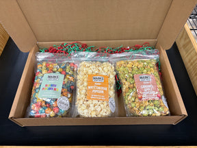 Marks Trading Company gourmet popcorn subscription box featuring three bags of rainbow, white cheddar, and apple flavors
