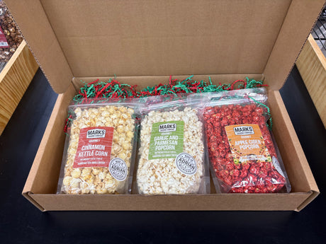 Marks Trading Company monthly gourmet popcorn gift box containing three bags of cinnamon, garlic parmesan, and apple cider